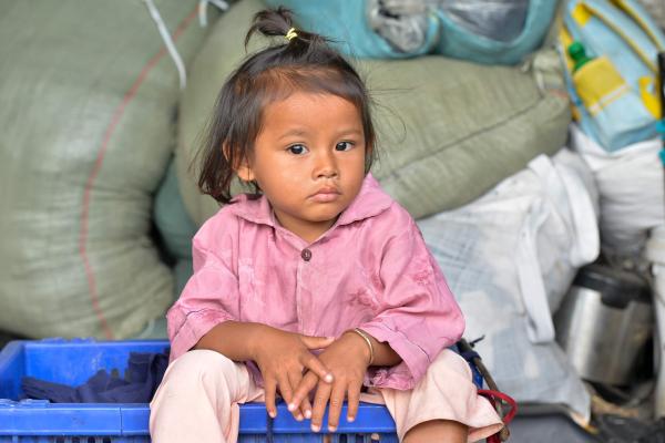 Une petite fille assise devant des sacs de riz distribués par PSE
